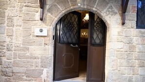 A stone building entrance with a dark wooden door and a sign above it. - Megiston House in Old Town Rhodes (Rhodes)