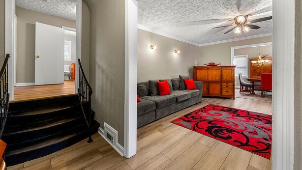 A living room with a gray sofa, red cushions, a red patterned rug, a wooden cabinet, and a ceiling fan. - 5 Minutes From Downtown Atlanta (Atlanta)