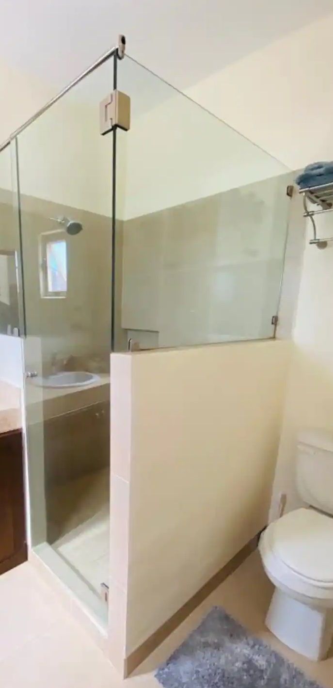 A bathroom with a glass-enclosed shower, a toilet, and a sink.