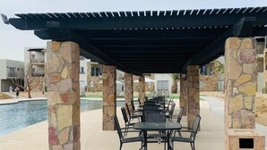 Eine Außenpatio-Terrasse mit Steinpfeilern, einer überdachten Sitzgelegenheit und einem Pool.