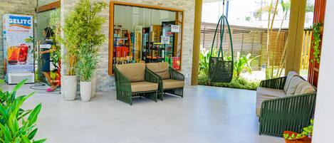 A spacious indoor area with seating arrangements, a glass storefront, and potted plants.
