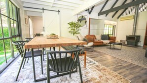A spacious living room with a large wooden dining table, black chairs, a sofa, and a fireplace. - LUMLEY ABODE : Bright (Bright)