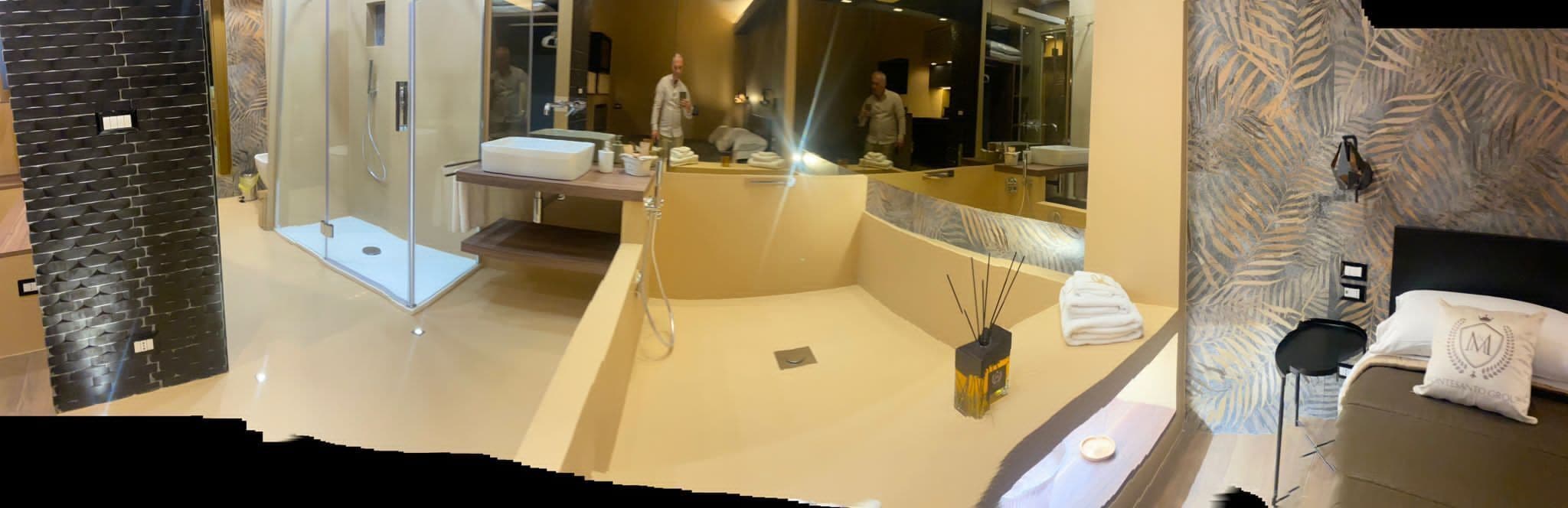 A modern bathroom with a glass shower enclosure, a large mirror, and a bathtub.