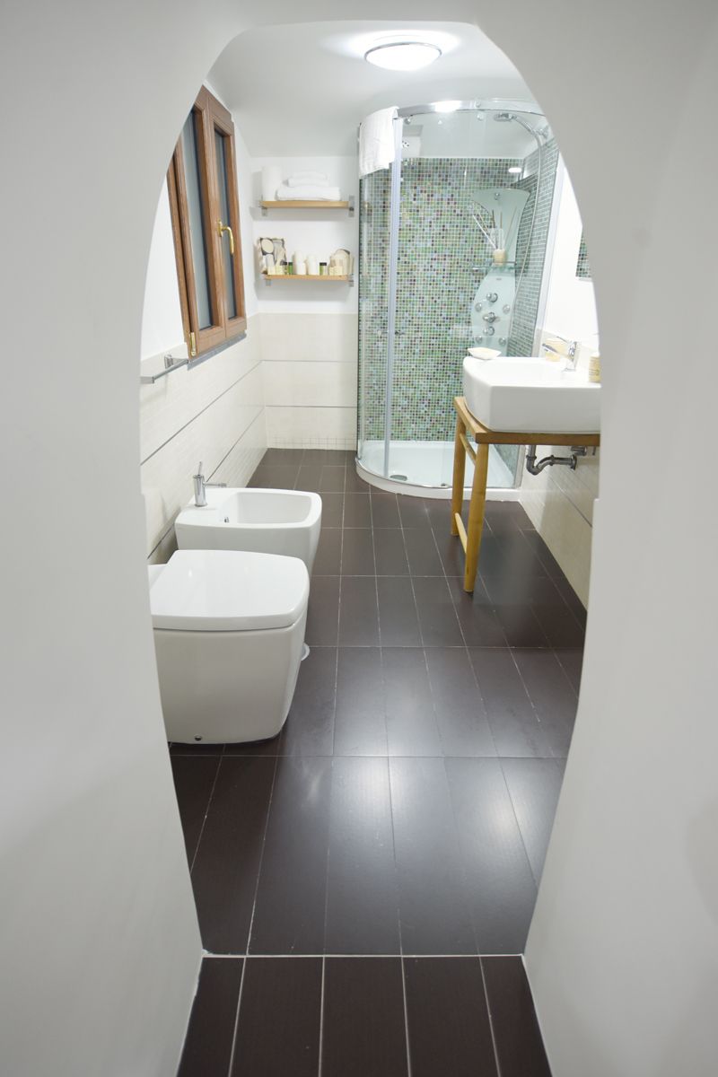 Une salle de bain moderne équipée d’une douche, de deux toilettes, d’un lavabo et d’un meuble-lavabo.