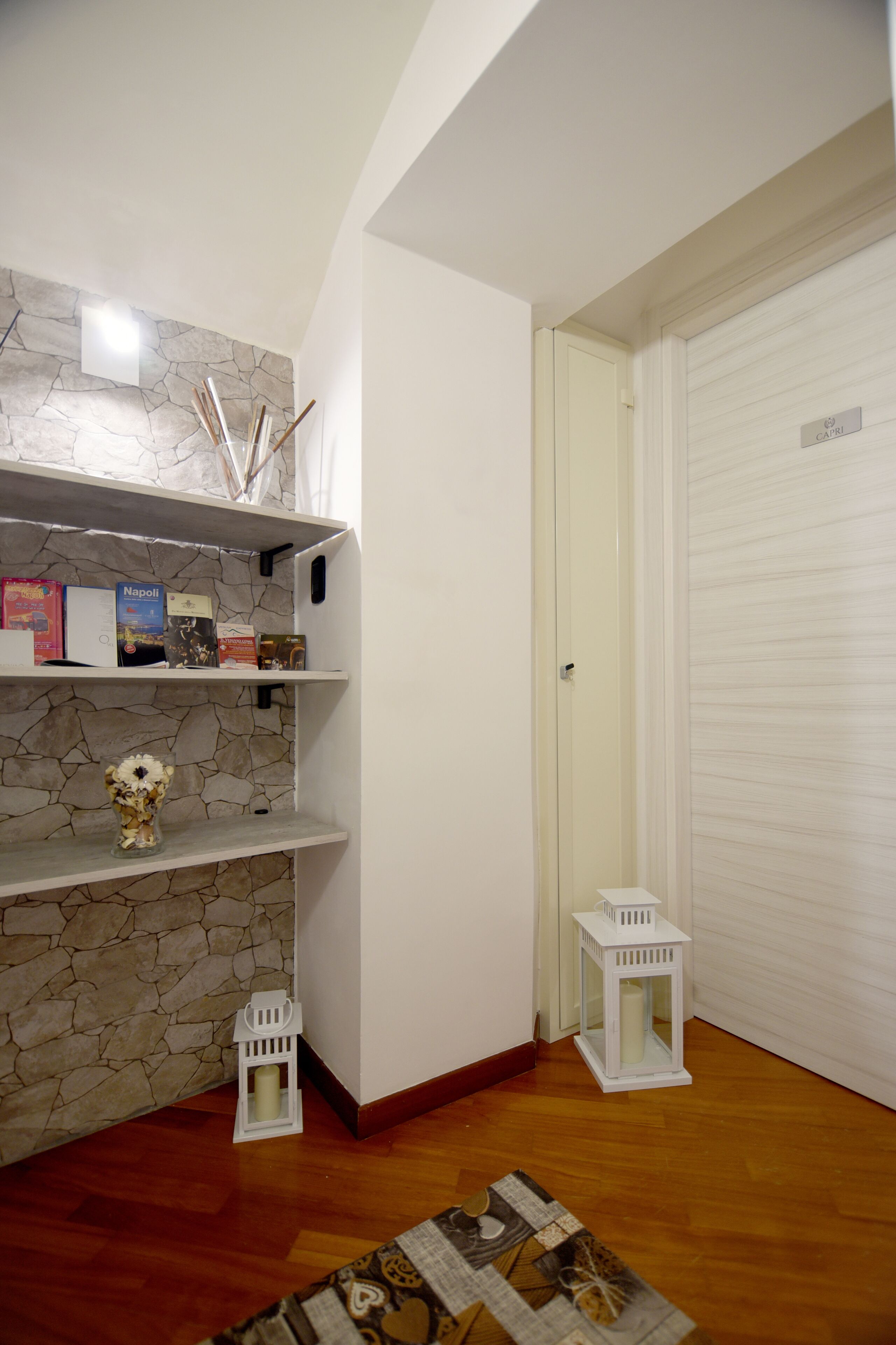 A room with a stone wall, a white door labeled 'CAPRI', and a wooden floor.