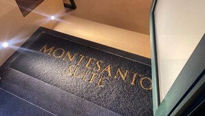 A black carpet with 'MONTSANTO SUITES' embossed in gold lettering. - Montesanto Group  (Naples)