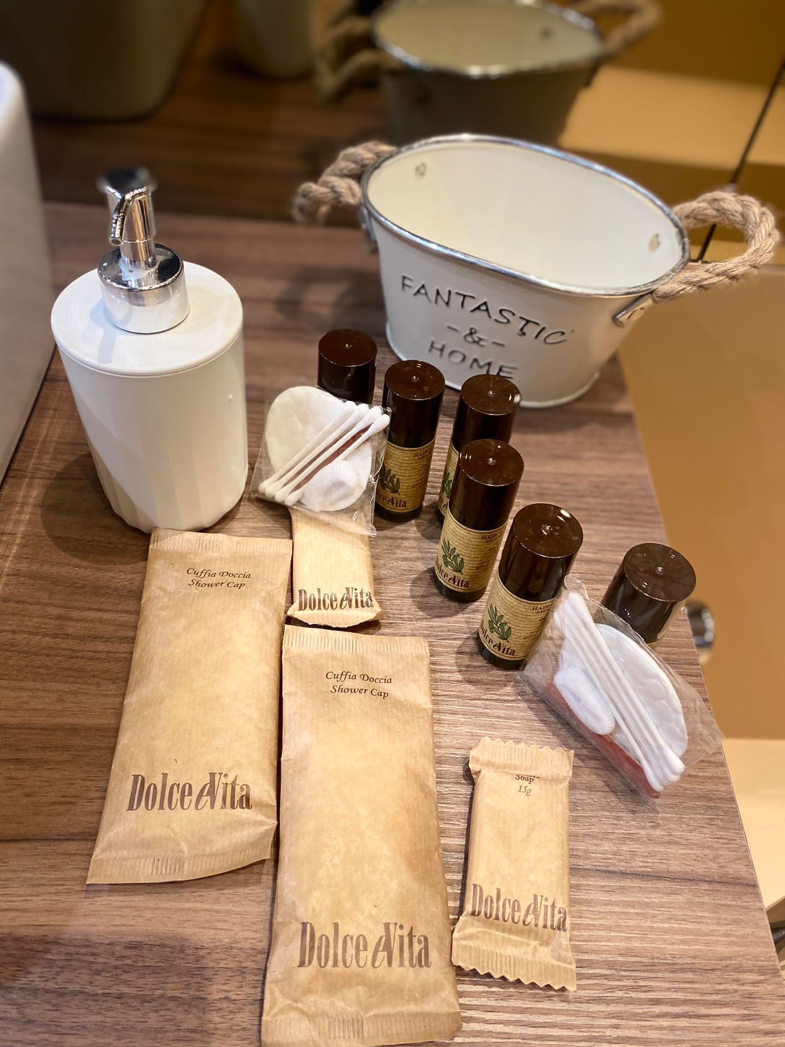 A wooden table with various toiletries including a shower cap, soap, and a bottle of lotion.