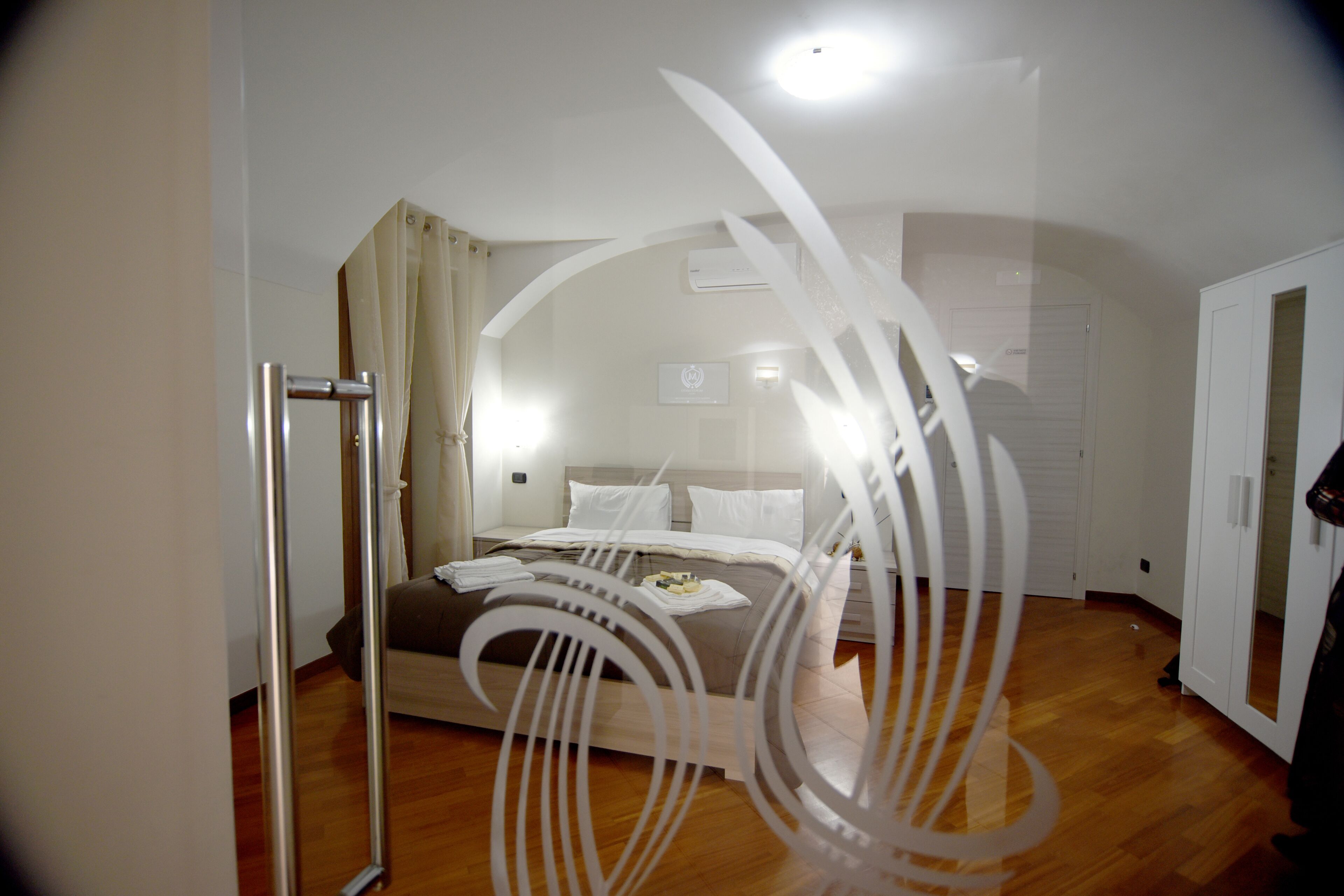 A bedroom with a bed, a wooden floor, a door, and a white decorative element.