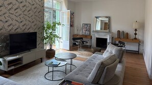 Un salon comprenant un téléviseur, un canapé, une table basse, une cheminée et une plante.