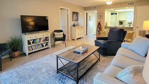 A living room with a flat-screen TV, a coffee table, a sofa, and a bookshelf.