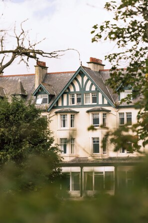 Un edificio grande de varios pisos con un estilo arquitectónico tradicional, que destaca por un techo a dos aguas y varias chimeneas.