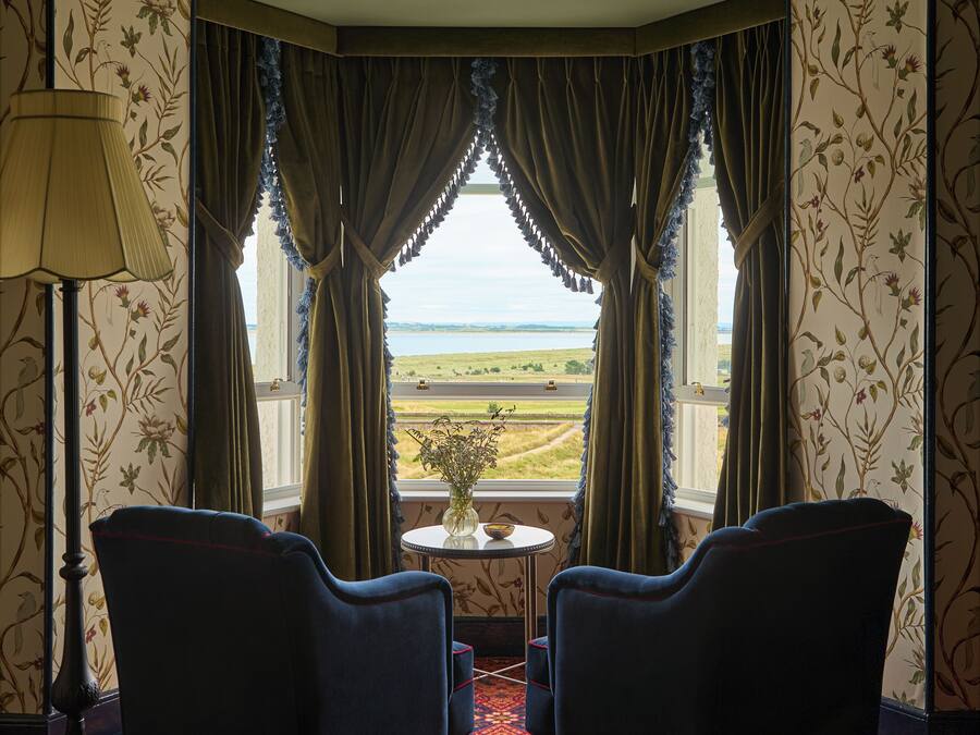 Una habitación con dos sillones mirando hacia una ventana con vistas a un paisaje.