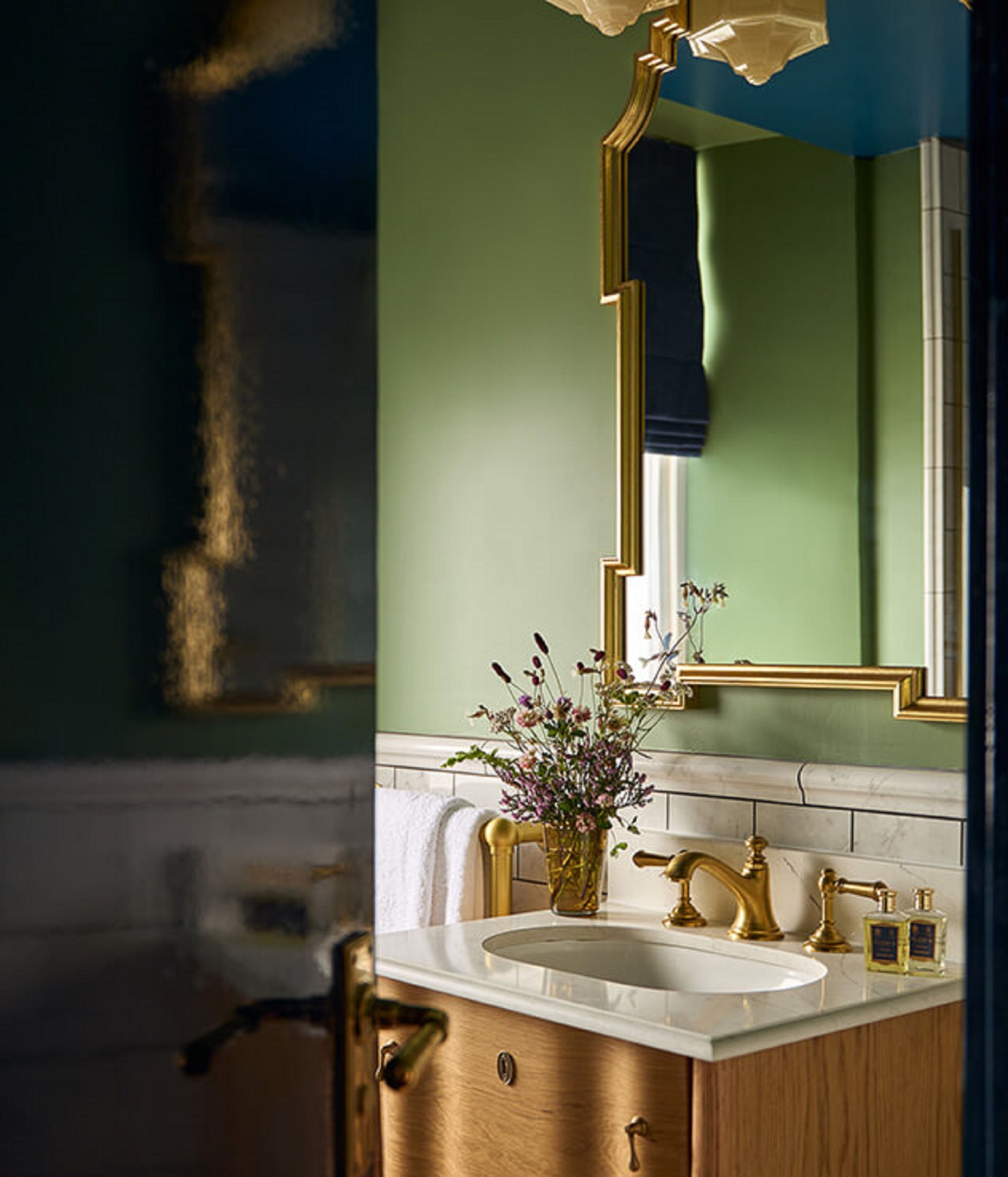 Une salle de bain avec un meuble-lavabo doré, un lavabo blanc et un miroir avec un cadre doré.