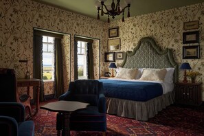 Un dormitorio con una cama grande, un escritorio, una silla y vistas por una ventana.