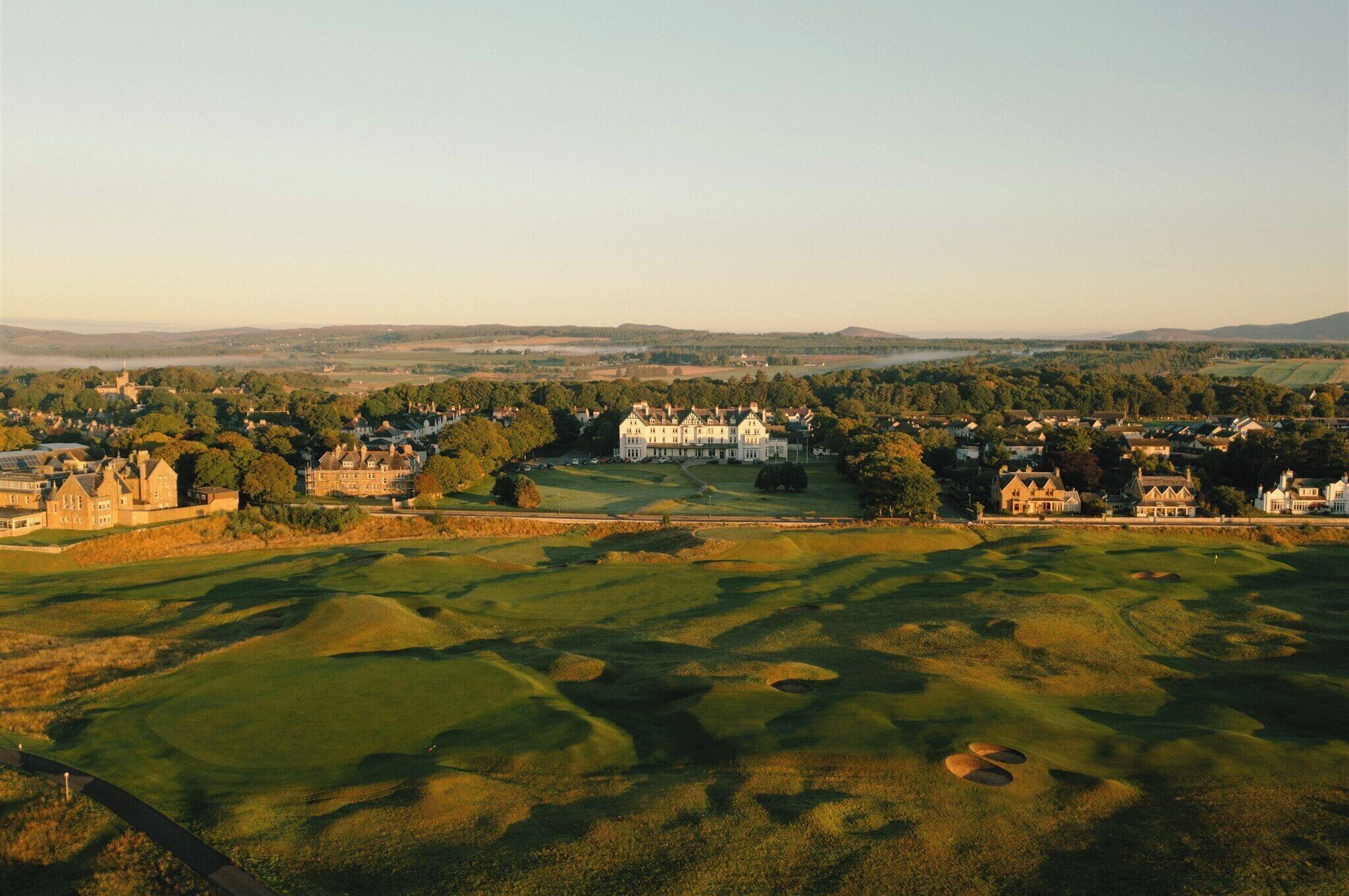 A golf course with a large clubhouse and surrounding buildings.