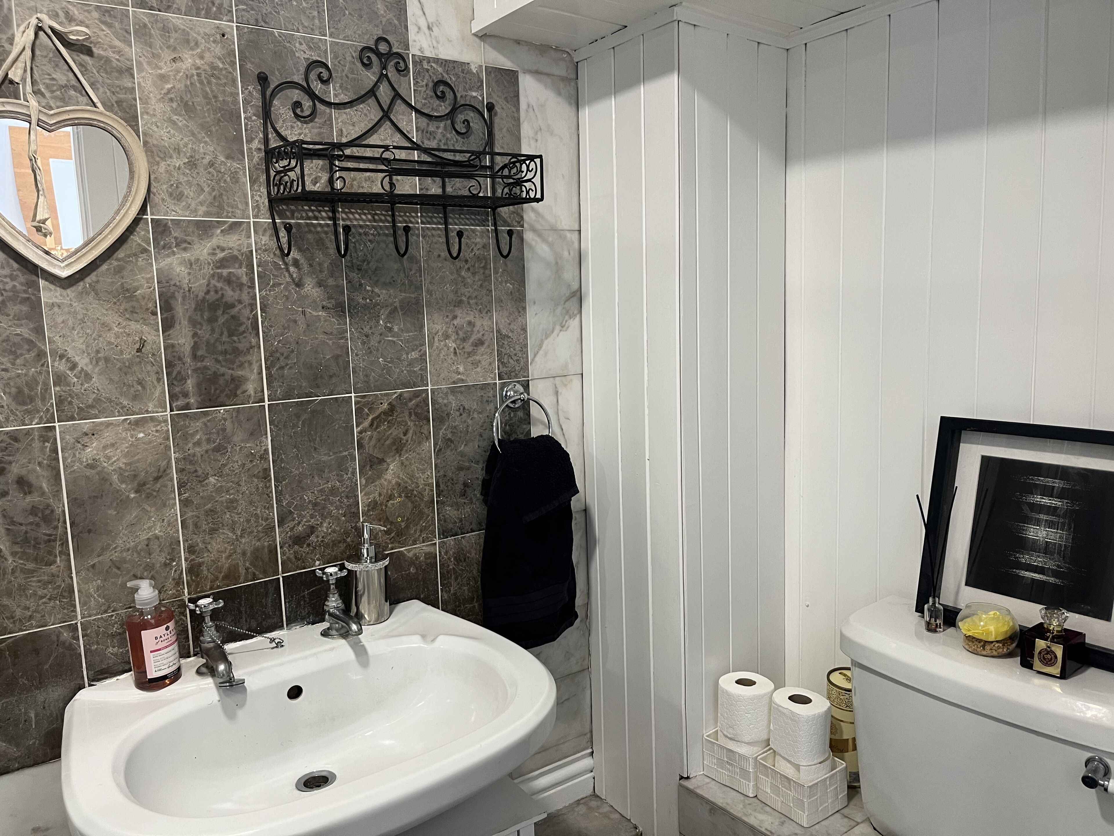 Une salle de bain avec un lavabo blanc, un miroir, un porte-serviettes et des toilettes.