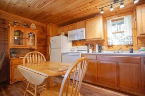 Kitchen features a central island, microwave, refrigerator, and sink with faucet, along with wooden cabinets and a dining area.