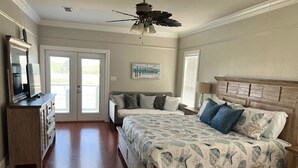 Een slaapkamer met een groot bed, een dressoir, een plafondventilator en een schilderij aan de muur.