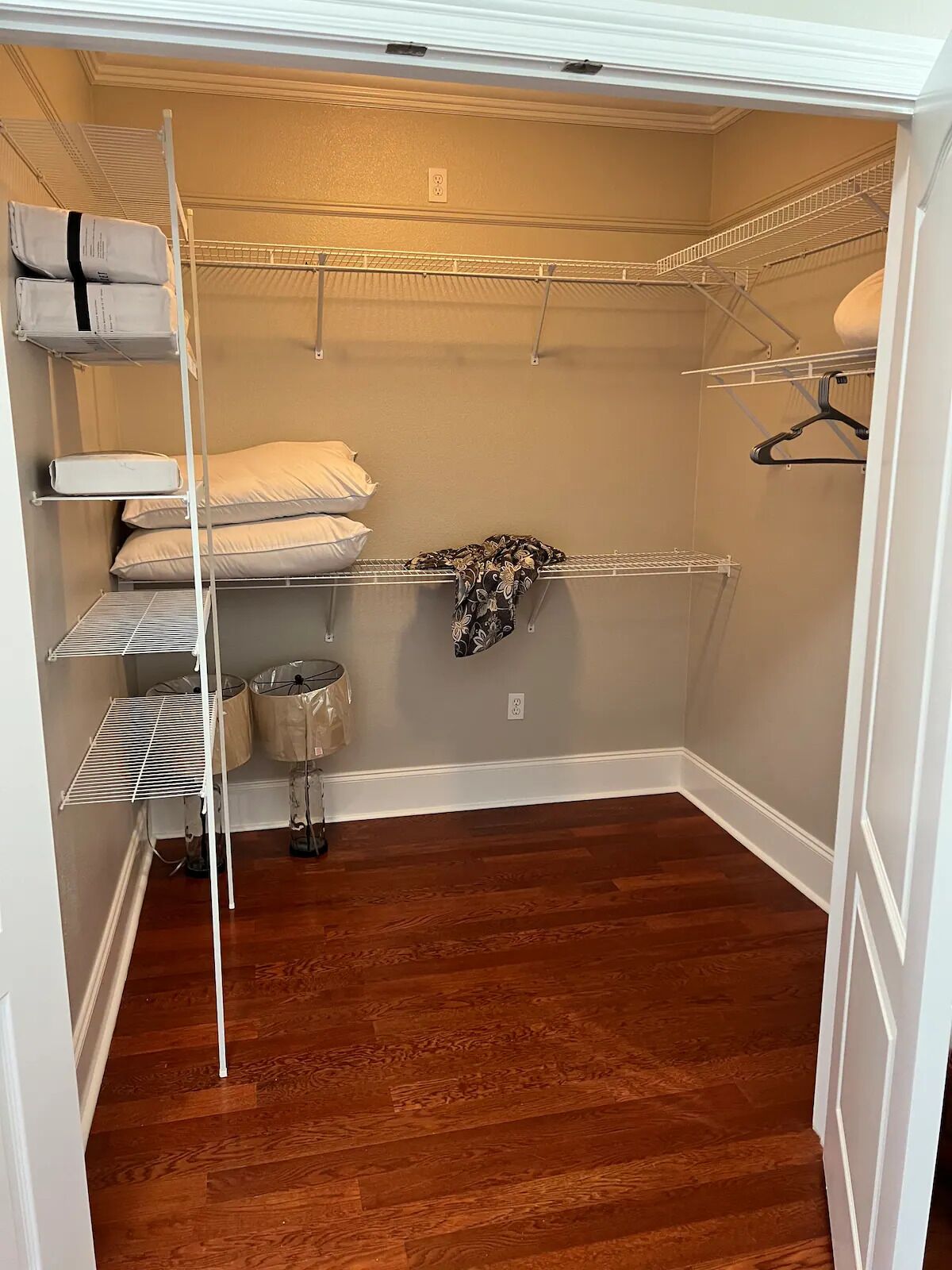 A walk-in closet with built-in shelves, a hanging rod, and a metal basket.