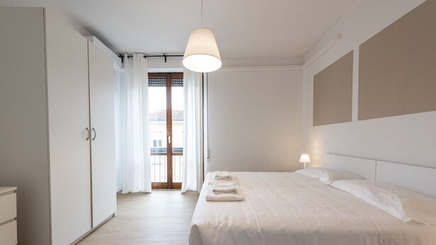 Un dormitorio con una cama grande, un armario y vistas a través de una puerta.