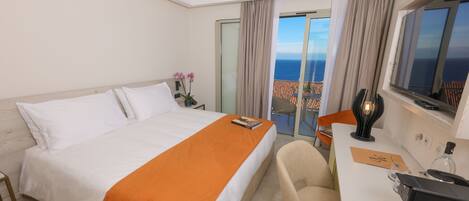 A hotel room with a bed, a desk, a chair, and a view of the ocean.