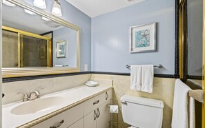 Une salle de bain avec un lavabo blanc, des toilettes, un porte-serviettes et un tableau encadré au mur.