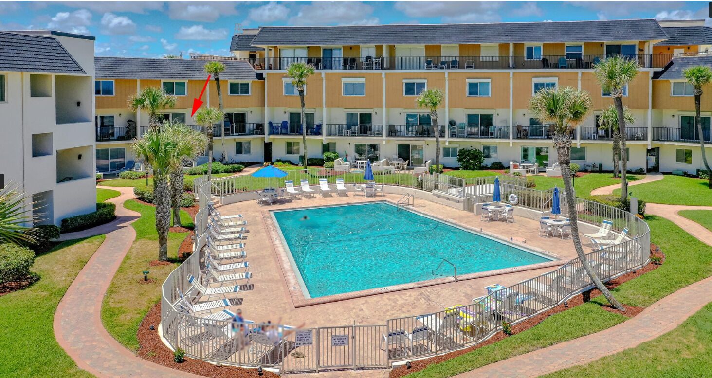Un hotel con piscina rodeada de tumbonas y palmeras.