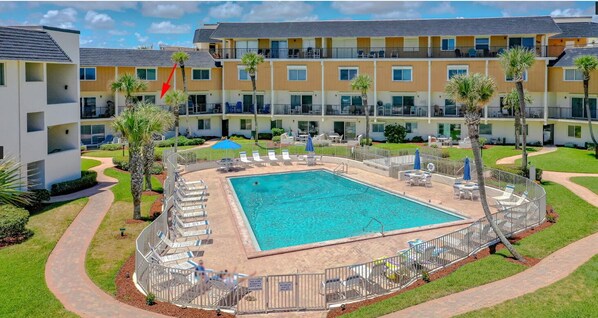 Un hôtel doté d’une piscine entourée de chaises longues et de palmiers.