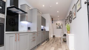 A modern kitchen with grey cabinets, a stainless steel range hood, and a wooden floor. - Ferry View (Poulton-le-Fylde)
