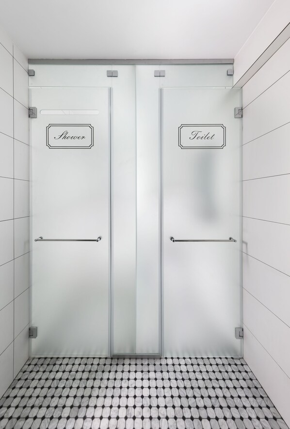 A bathroom with two doors labeled "Shower" and "Toilet" with towel racks.