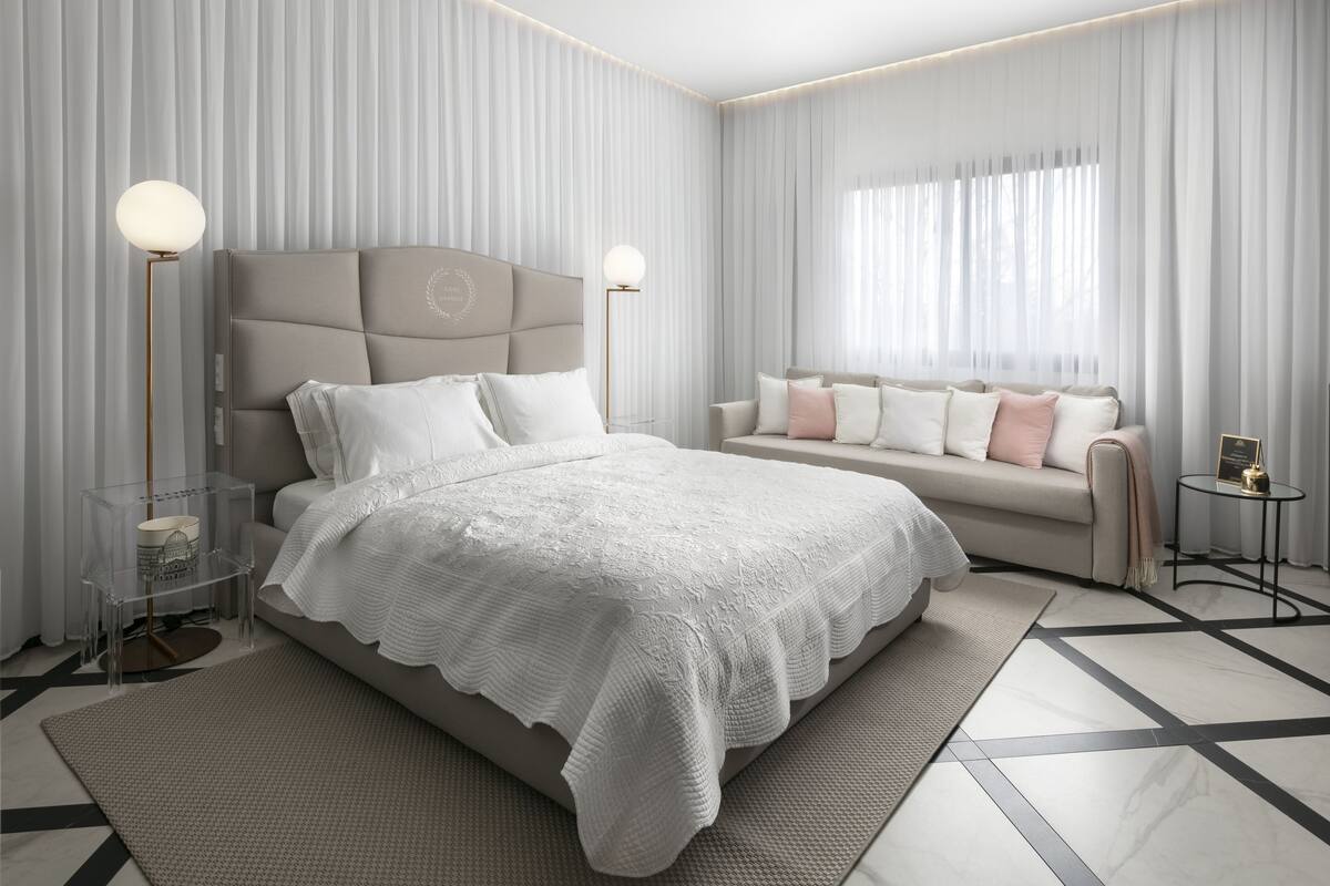Une chambre moderne avec un grand lit, un canapé et deux tables de chevet avec des lampes.