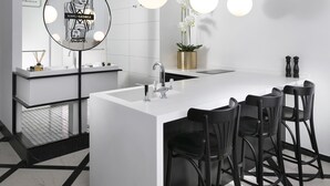 A modern kitchen with a central island, black bar stools, and pendant lighting. - King George Suites (Jerusalem)