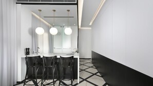 A modern kitchen with a white countertop, black chairs, and pendant lights. - King George Suites (Jerusalem)