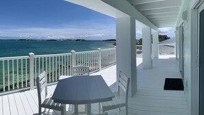 A covered outdoor area with a white railing, a table, and chairs. - Luxury oceanfront villa 1BR, protected dock, private & gated peninsula (Marsh Harbour)