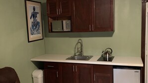 A compact kitchen with wooden cabinets, a microwave, a sink, and a refrigerator. - Entire Guest Suite - 1 bedroom (Nassau)