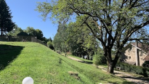 A grassy slope with a lamp post, a stone building, and a tree. - Domaine Le Colombié  (Gorses)