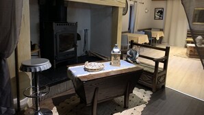 A cozy room with a fireplace, a table with a cake, and a chair. - Domaine Le Colombié  (Gorses)