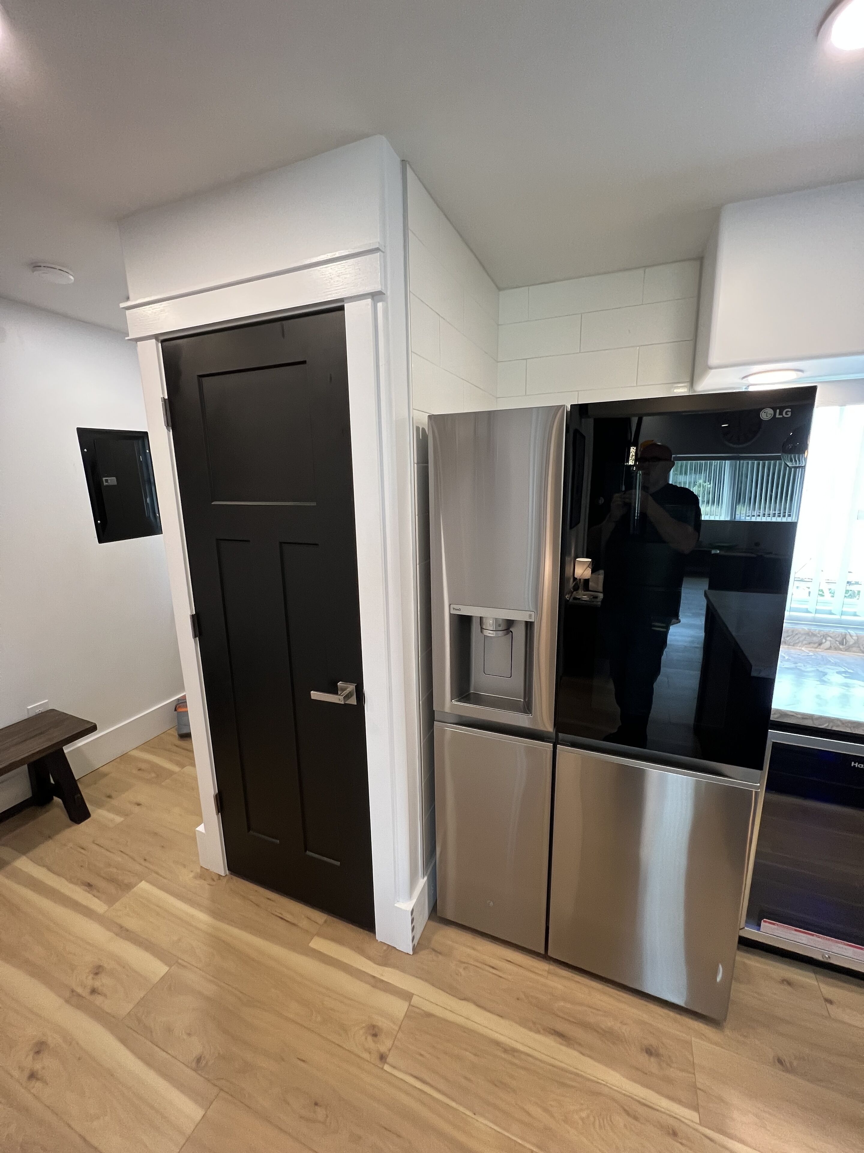 A modern kitchen with a stainless steel refrigerator, a water dispenser, and a bench.