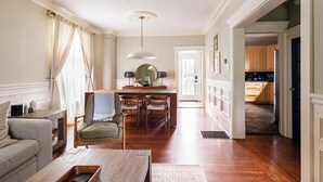 Un salon spacieux doté d’un parquet, d’un canapé, d’une table basse et d’un coin repas avec une table et des chaises.