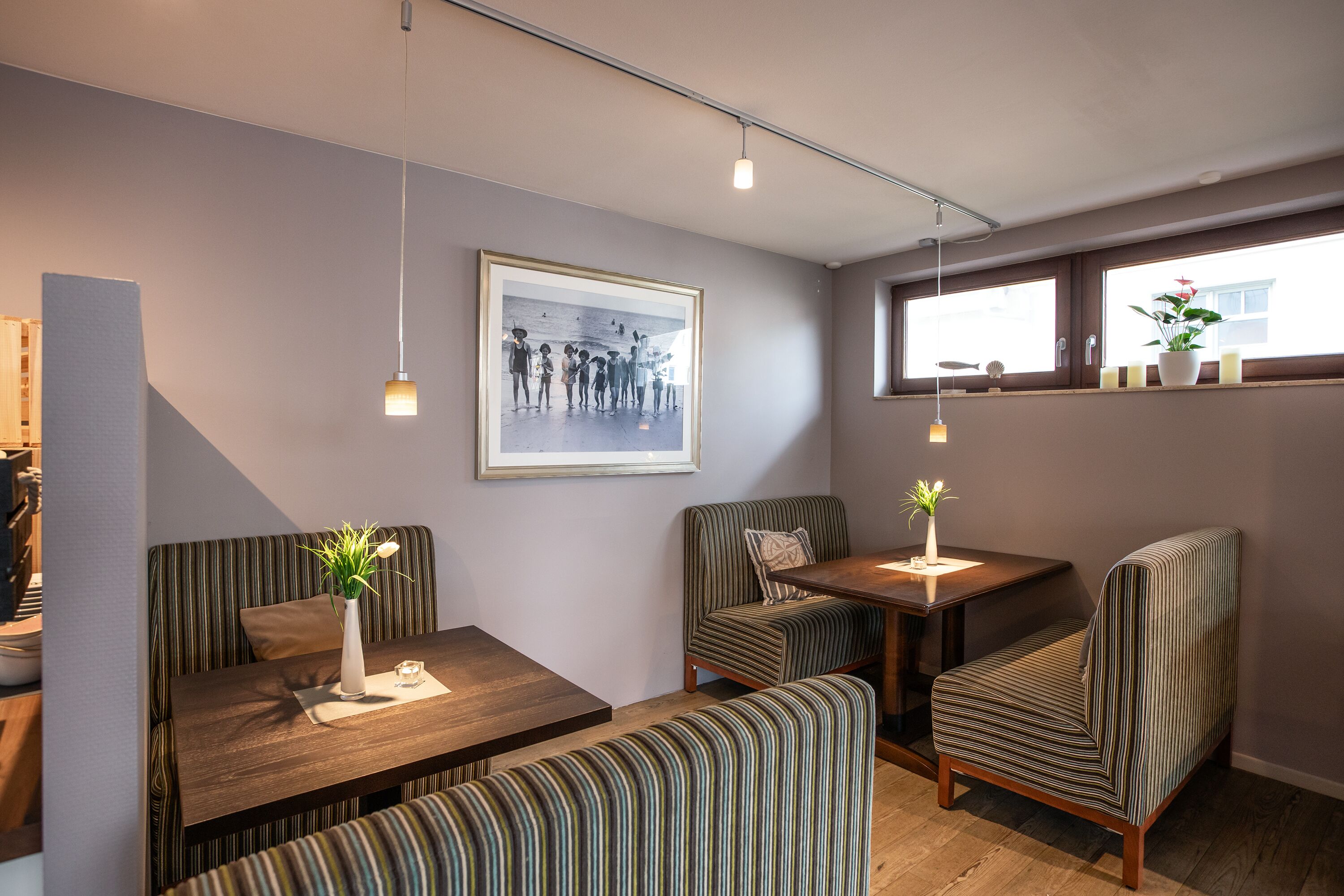A modern dining area with striped upholstered chairs, a wooden table, and a framed photograph on the wall.