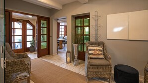 Ein geräumiger Wohnbereich mit Rattanmöbeln, einem großen Fenster mit smaragdgrünen Scheiben und einem weißen Schrank an der Wand.