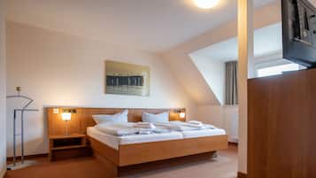Habitación de hotel moderna con cama de madera, lámparas de noche, un cuadro en la pared y vistas al exterior.