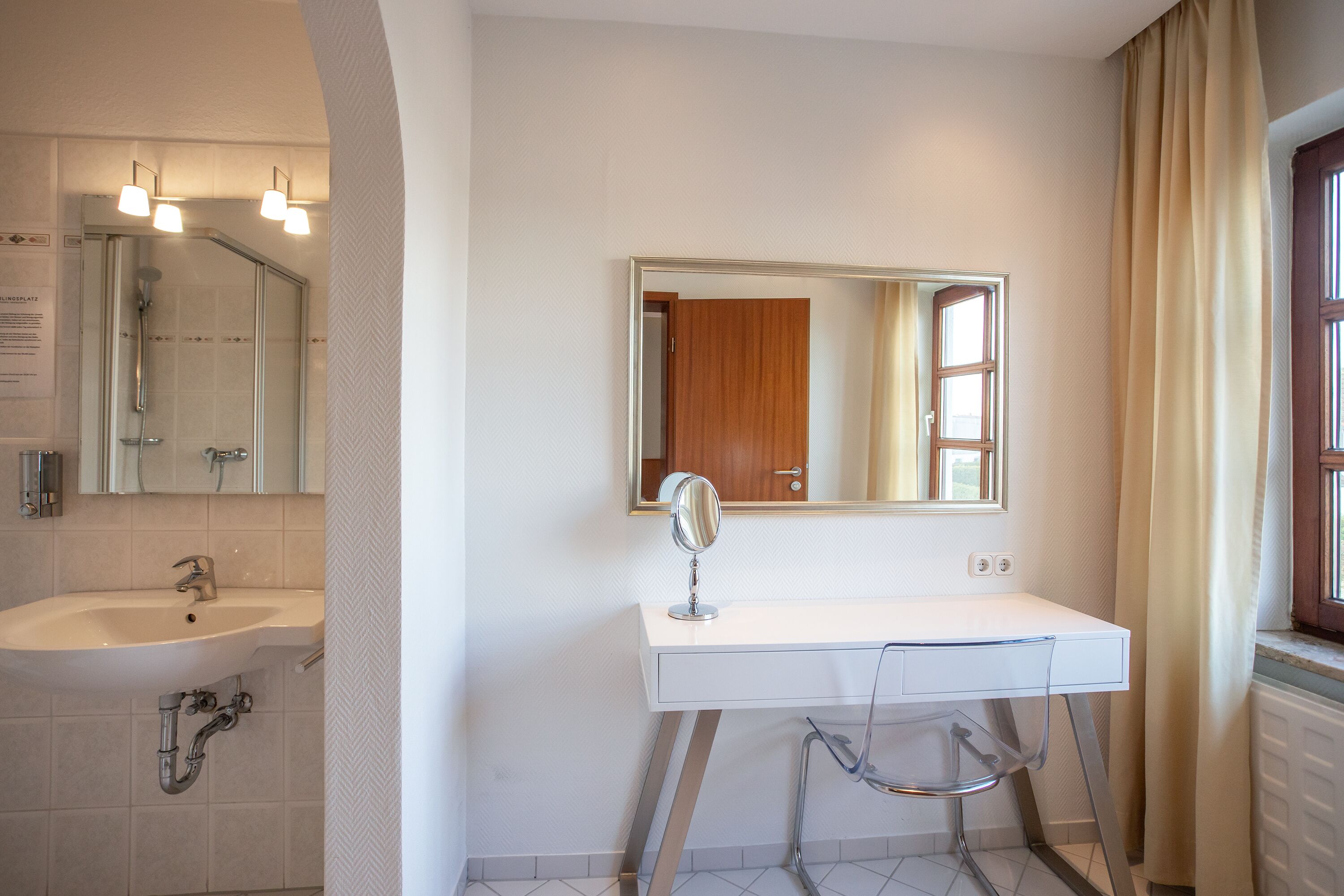 Une salle de bain avec un lavabo blanc, un miroir et une douche.