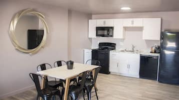 A compact kitchen with white cabinets, a black stove, and a stainless steel refrigerator.