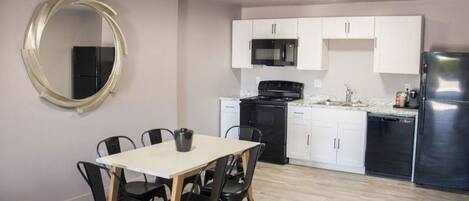 A compact kitchen with white cabinets, a black stove, and a stainless steel refrigerator.
