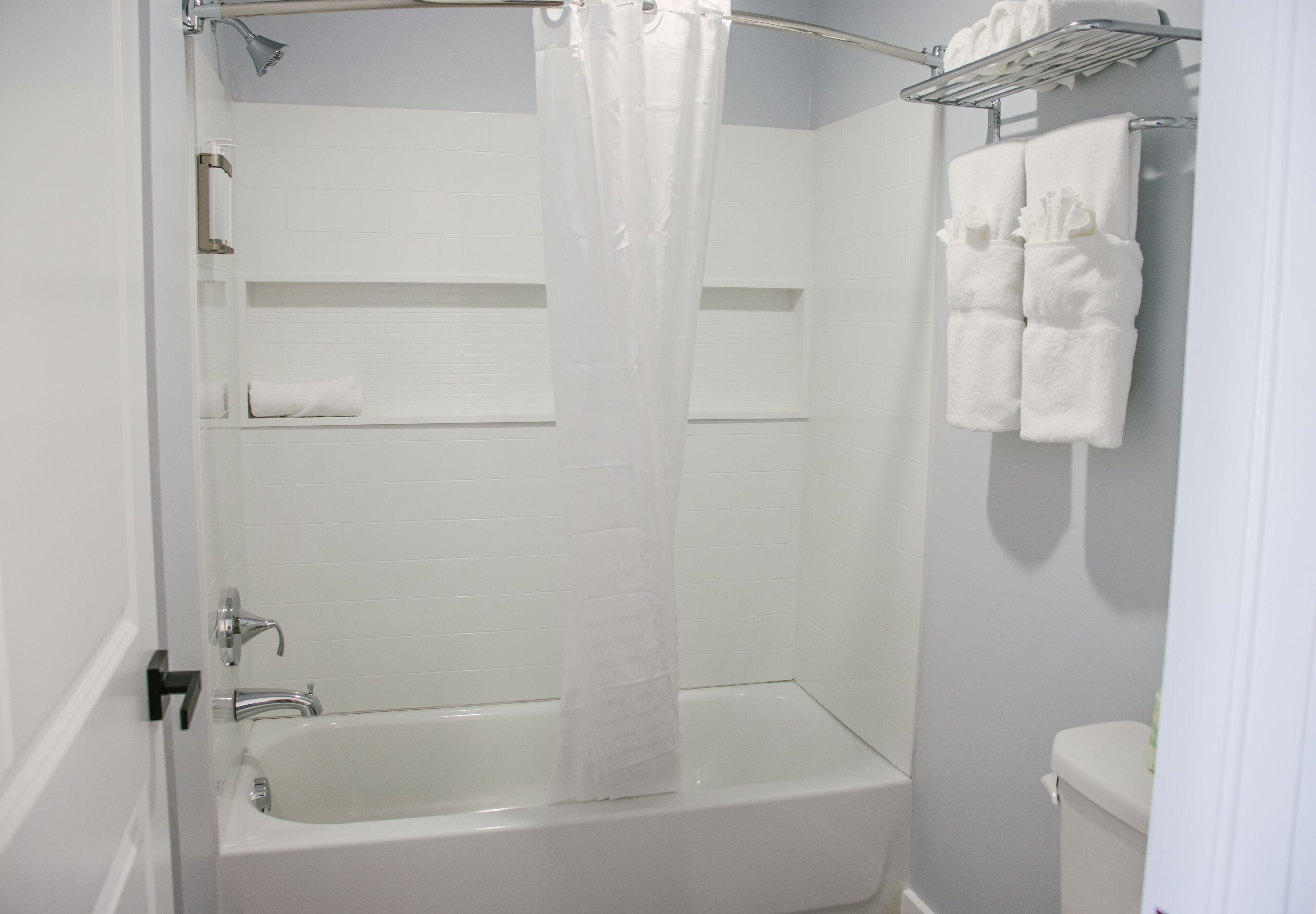 Une salle de bain équipée d’une baignoire, d’un rideau de douche, d’un porte-serviettes et de toilettes.