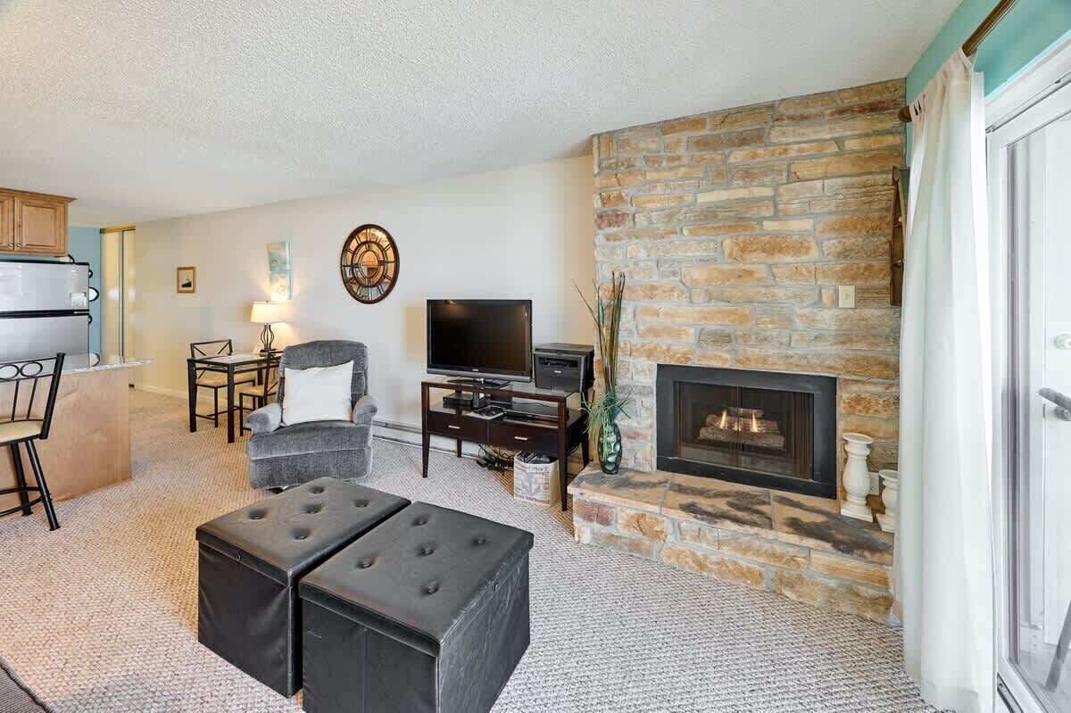 A living room with a stone fireplace, a television, and a dining area with a table and chairs.