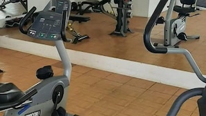 A gym with exercise equipment including a treadmill, stationary bikes, and weight machines. - Departamentos FVD (Cabo San Lucas)
