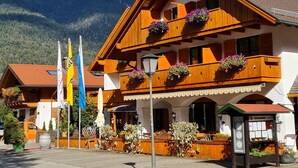 Un edificio de madera tradicional con balcones, banderas y macetas de flores.