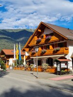 A traditional wooden building with balconies, flags, and flower baskets.